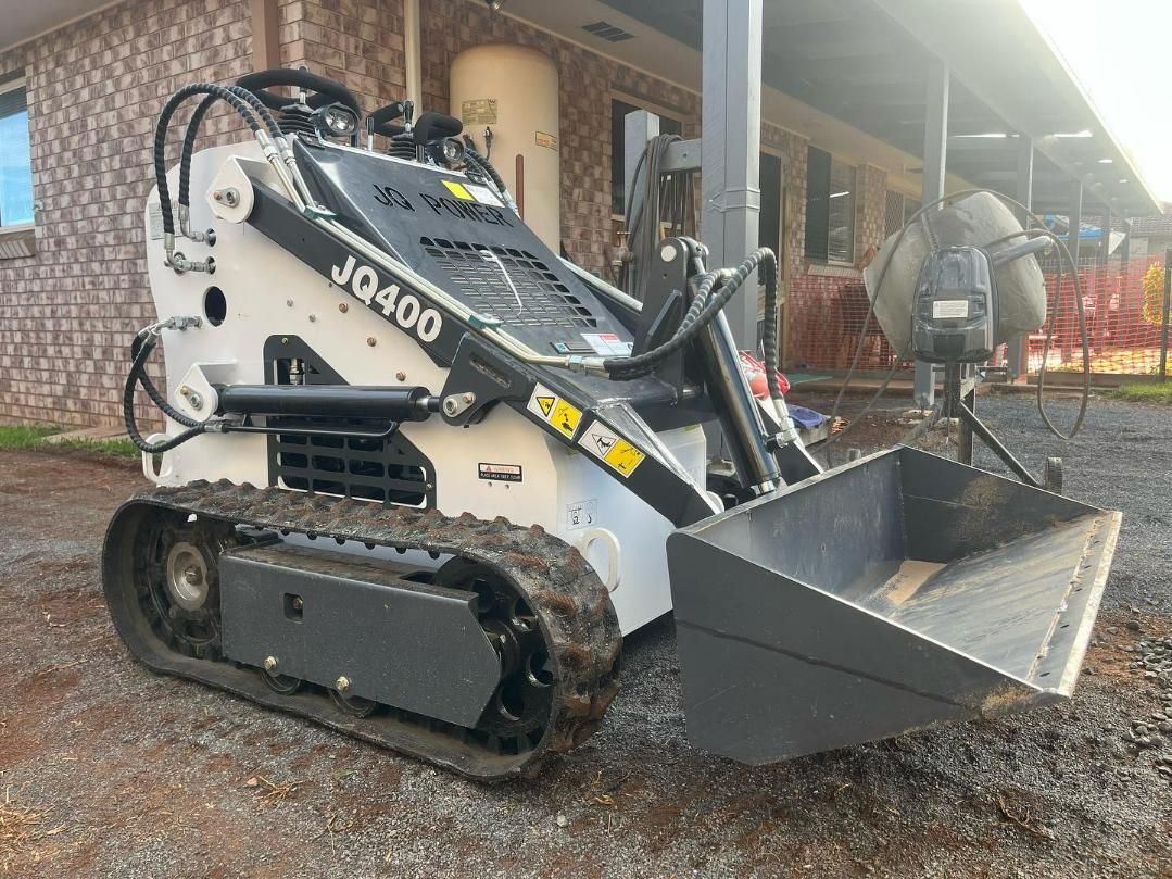 A Small Bulldozer with A Bucket Is Parked in Front of A Building — ZBM Constructions in Wollongbar, NSW