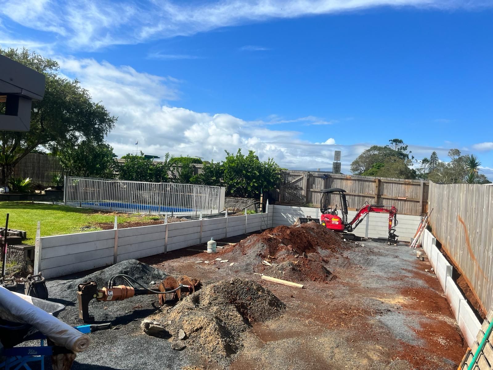 A White and Orange Skid Steer Is Parked in A Dirt Field — ZBM Constructions in Wollongbar, NSW