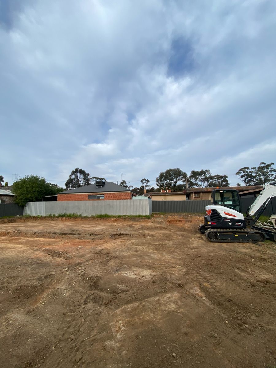 A bulldozer is sitting in the middle of a dirt field.