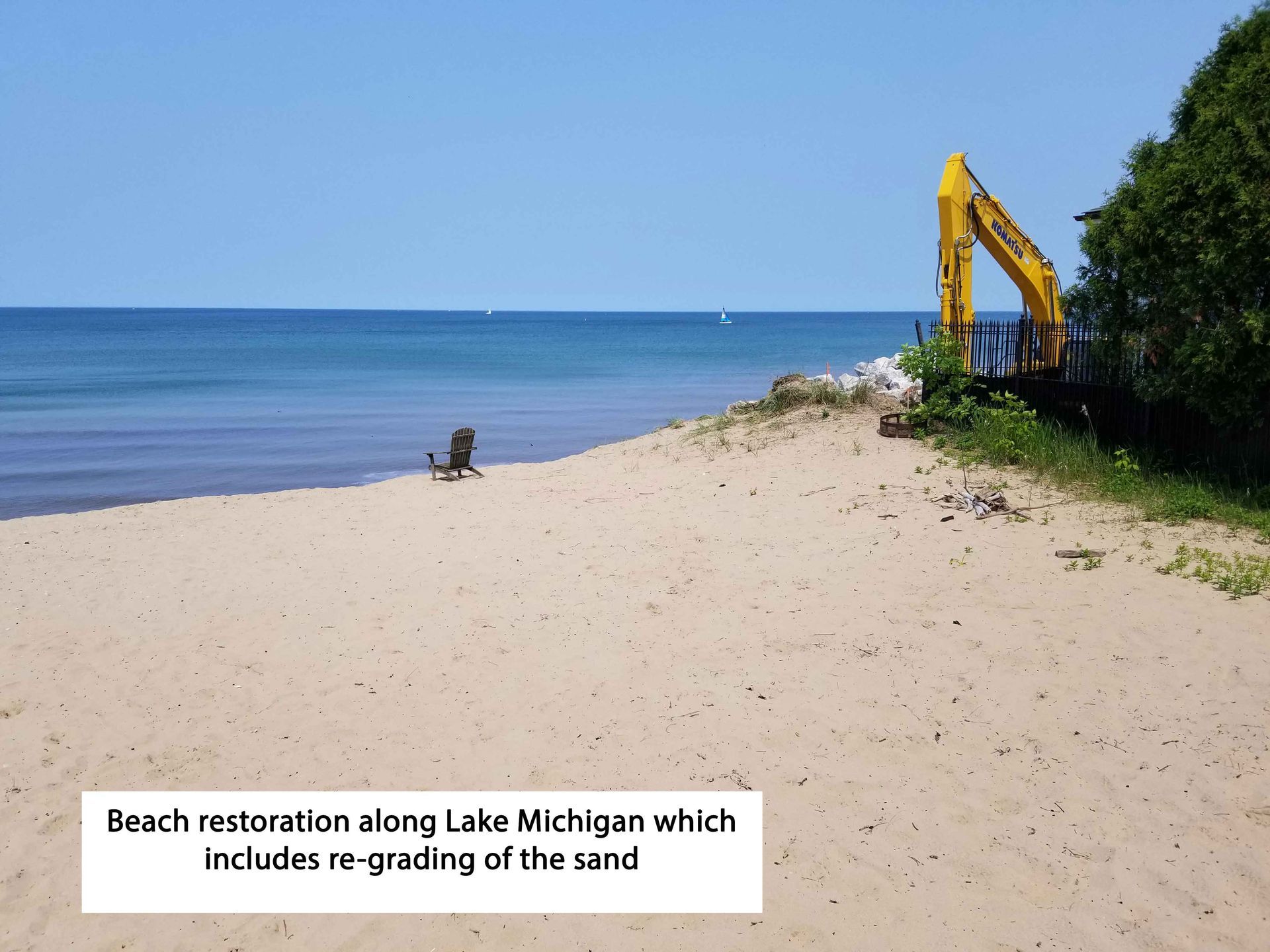 Beach restoration on Lake Michigan: excavator on sand, blue water, clear sky.
