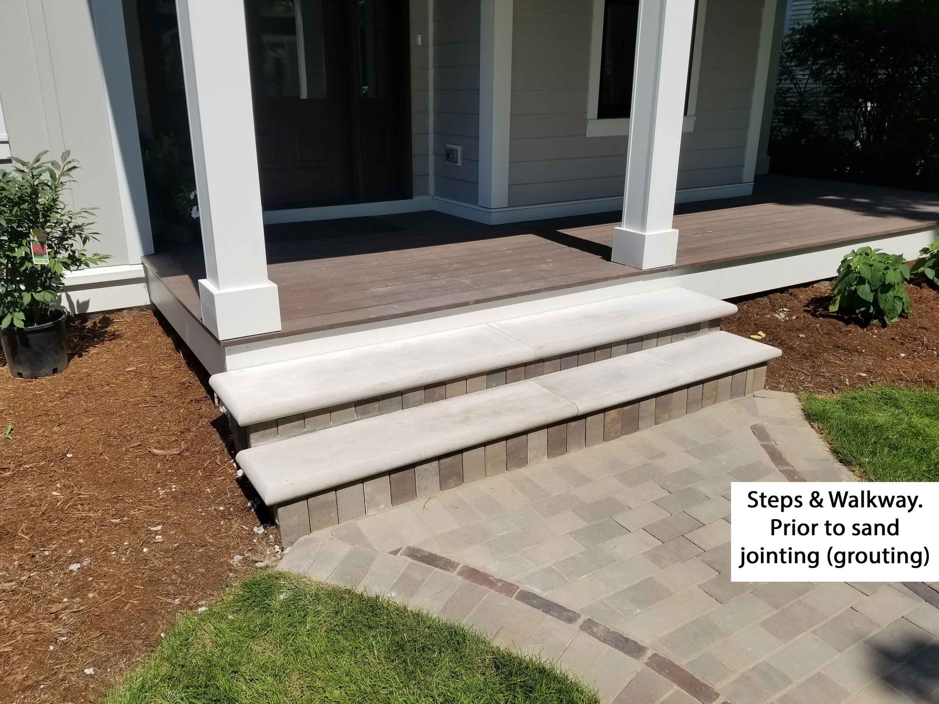 Steps and walkway of a home before sand and jointing. Light steps, pavers lead to porch.