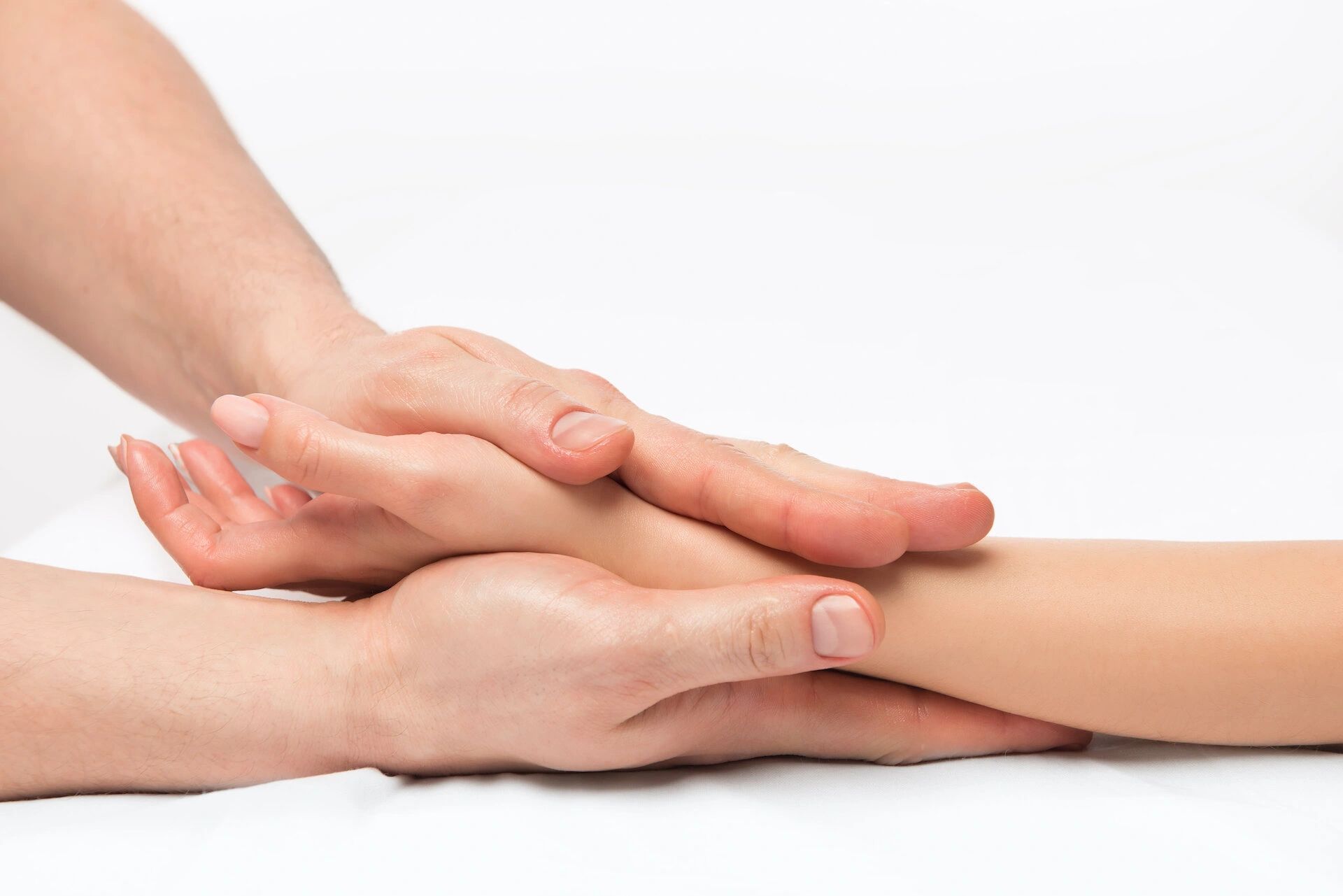 Hands gently holding another hand, possibly providing comfort or treatment. White background.