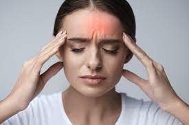 Woman with closed eyes, touching her forehead, red area indicates a headache.