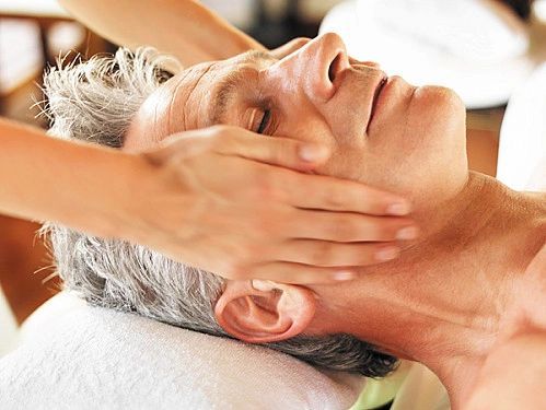 Person receiving face and neck massage. Hands on face and neck. Relaxed expression.