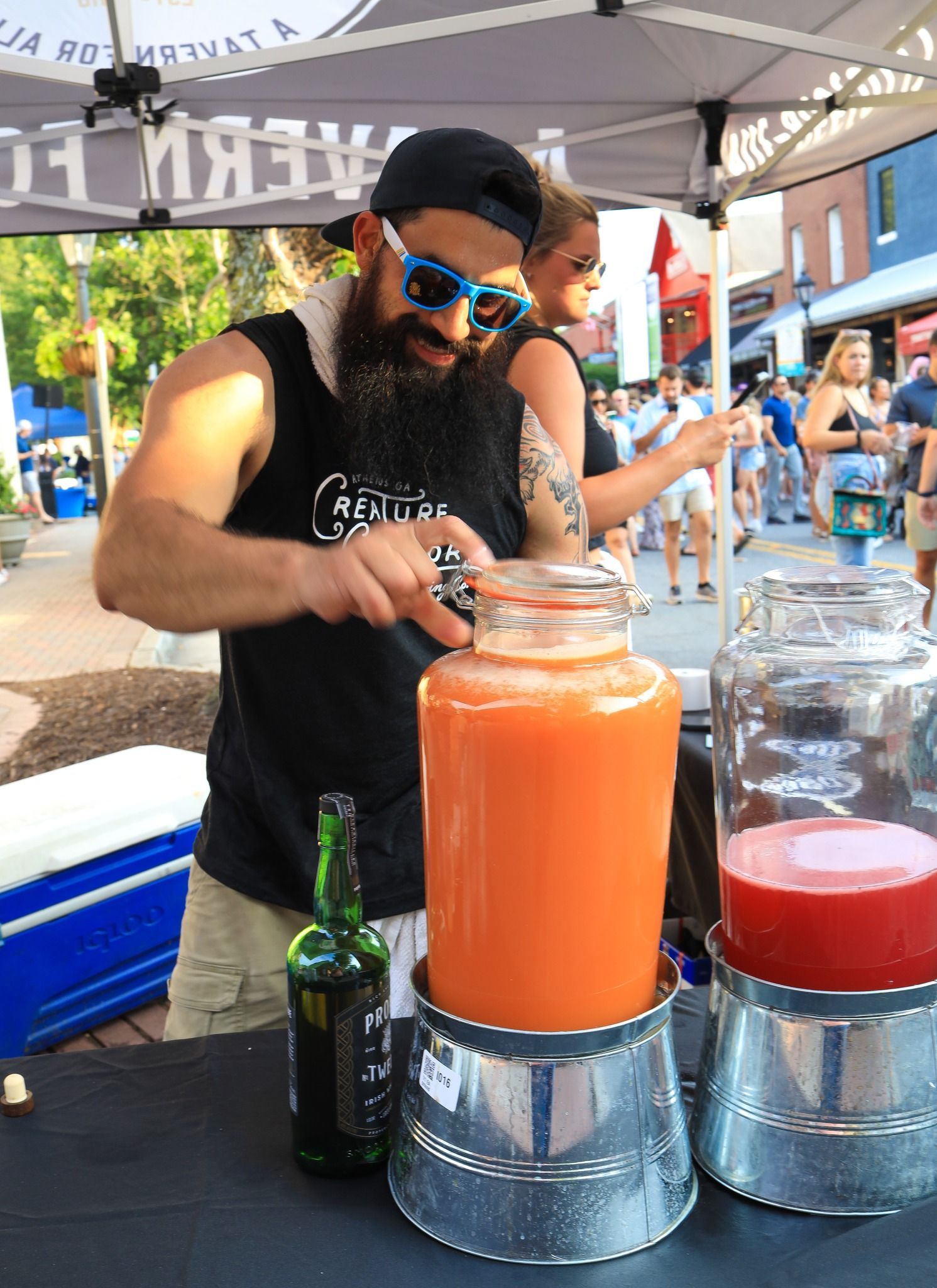 A man with a beard is pouring a drink into a jar.