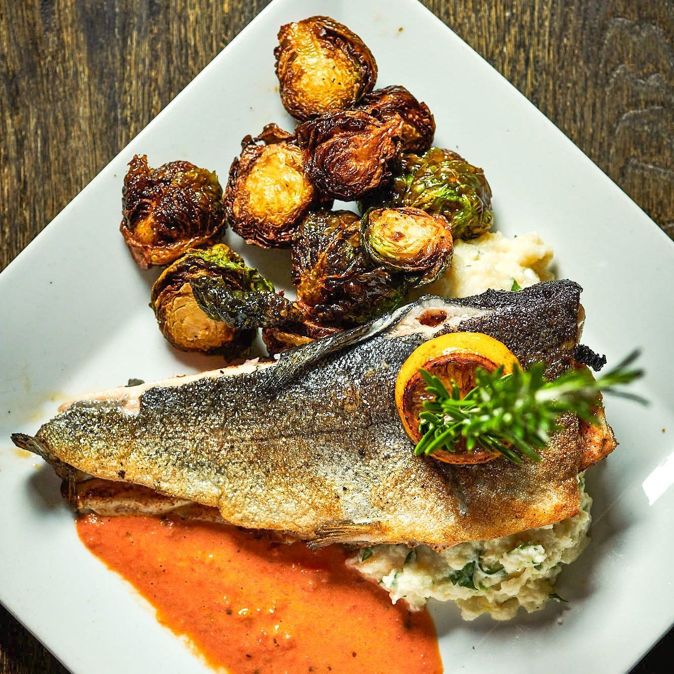 A white plate topped with a piece of fish and vegetables