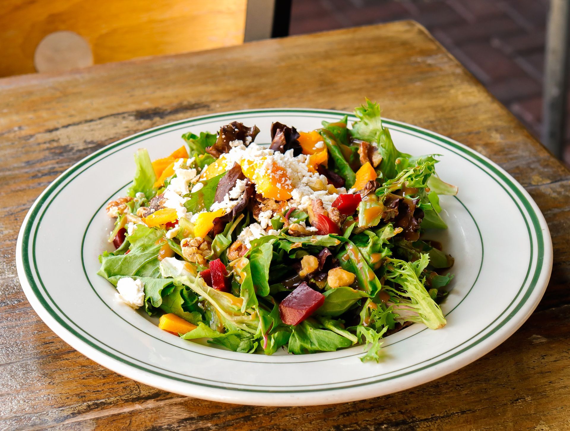 A white plate topped with a salad on a wooden table.