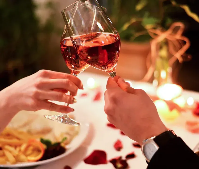 Un hombre y una mujer brindan con copas de vino en una mesa.
