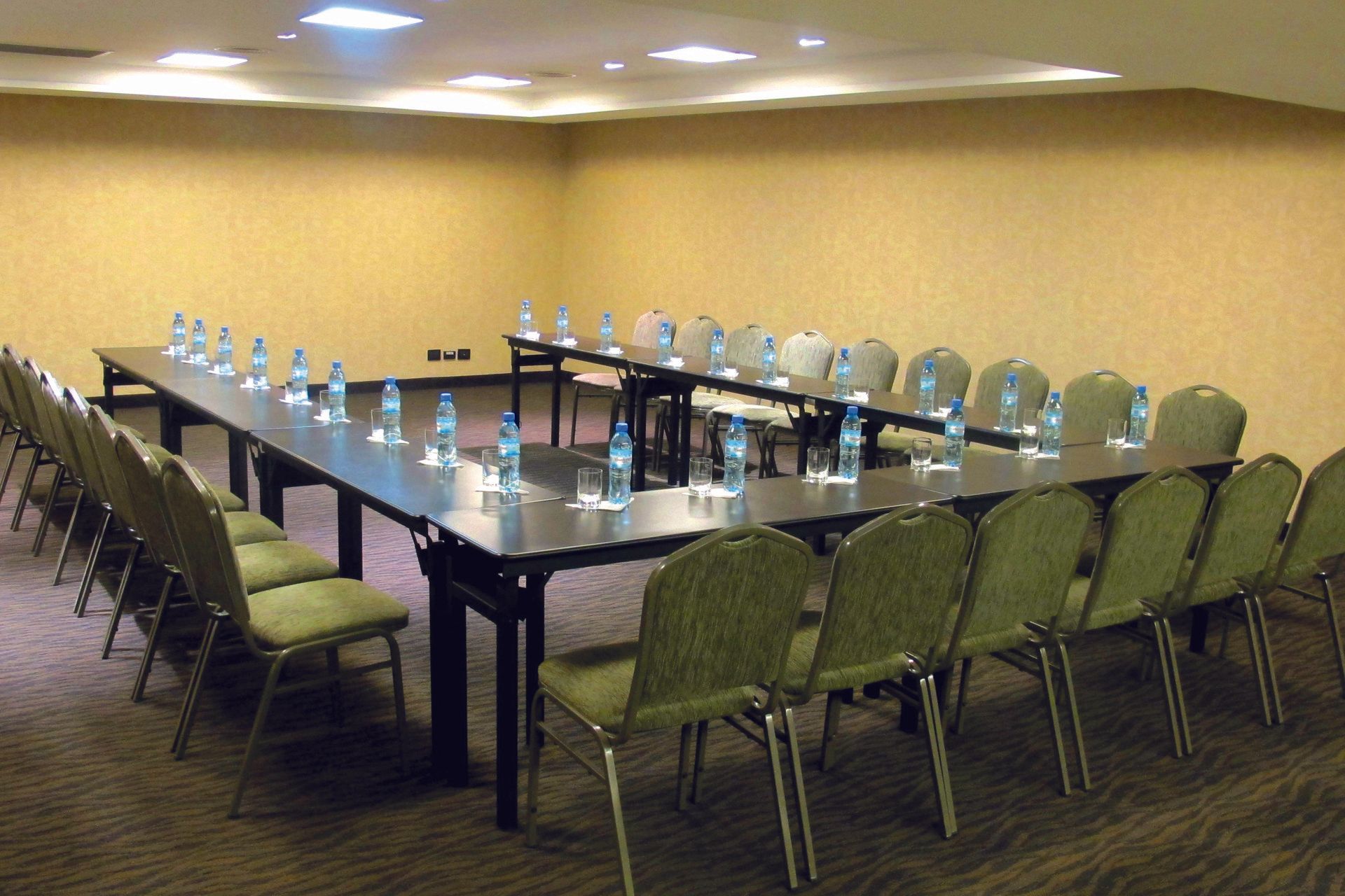 Una sala de conferencias con mesas y sillas preparadas para una reunión