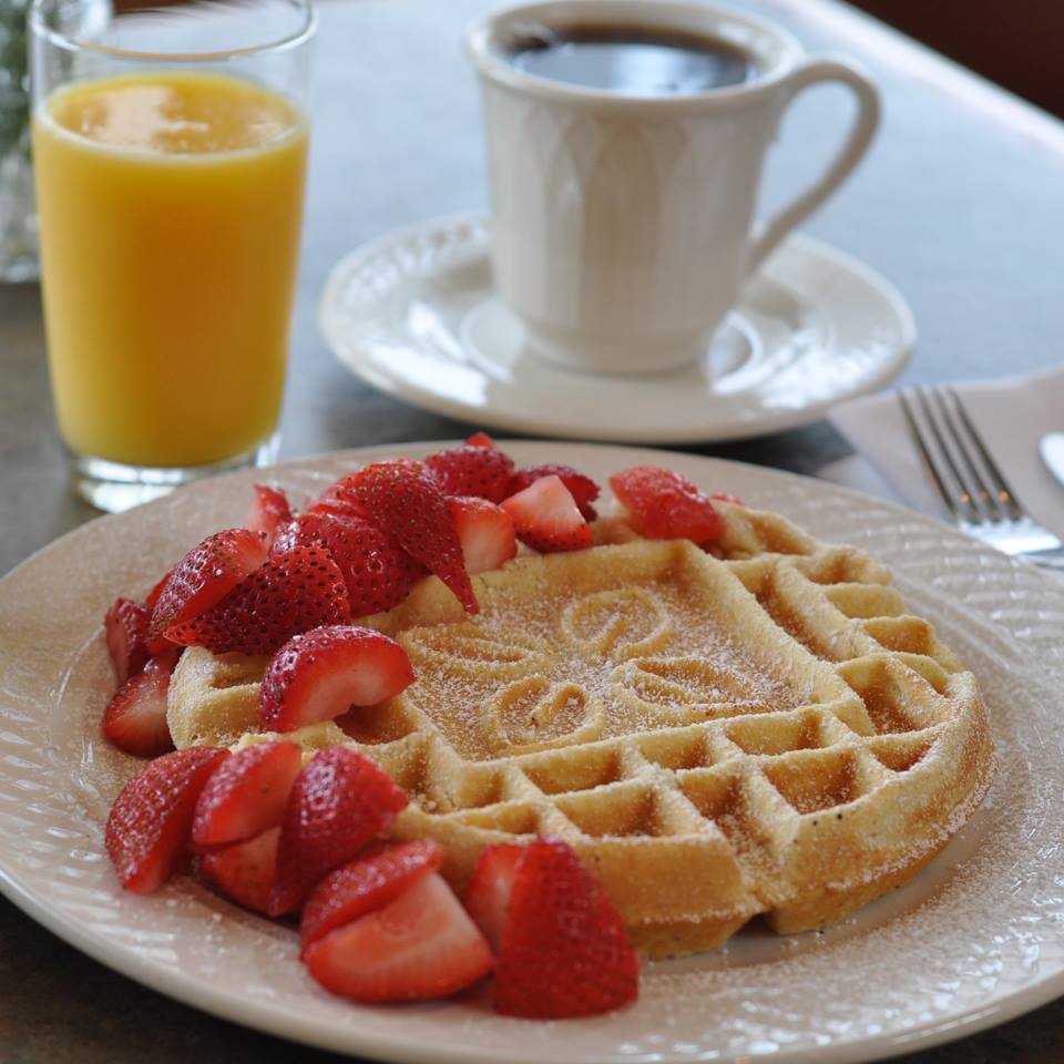 Un waffle con fresas y azúcar en polvo en un plato