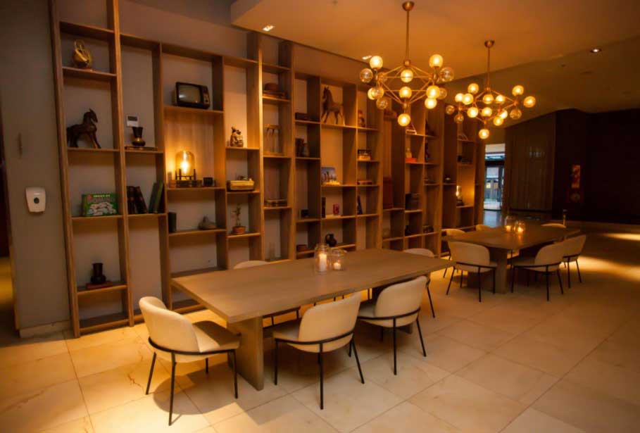 Un comedor con mesa y sillas frente a una estantería.