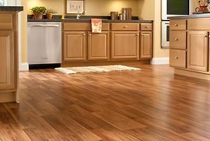 Wooden kitchen floor with light brown cabinets and appliances.