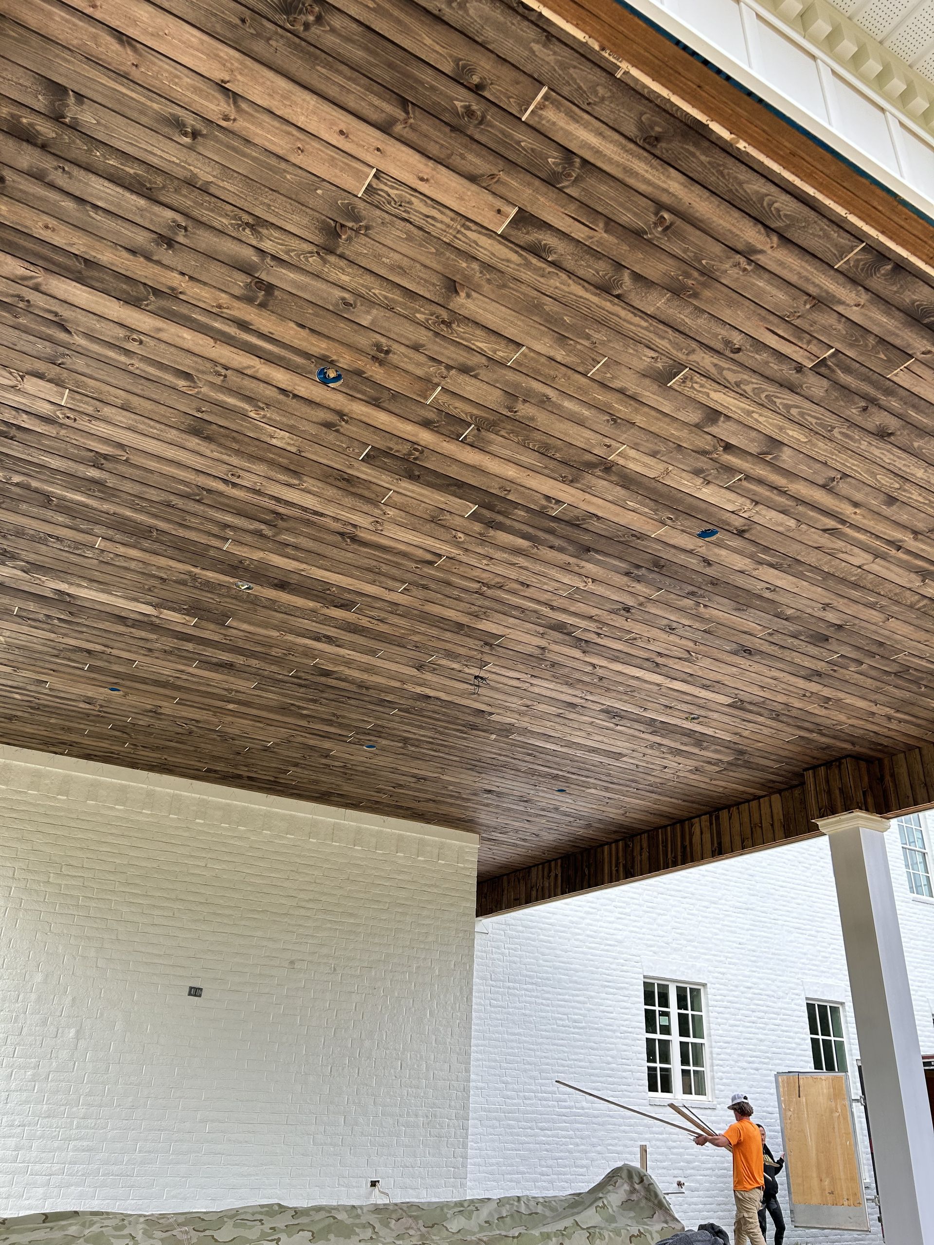A man is painting the ceiling of a building with a brush.