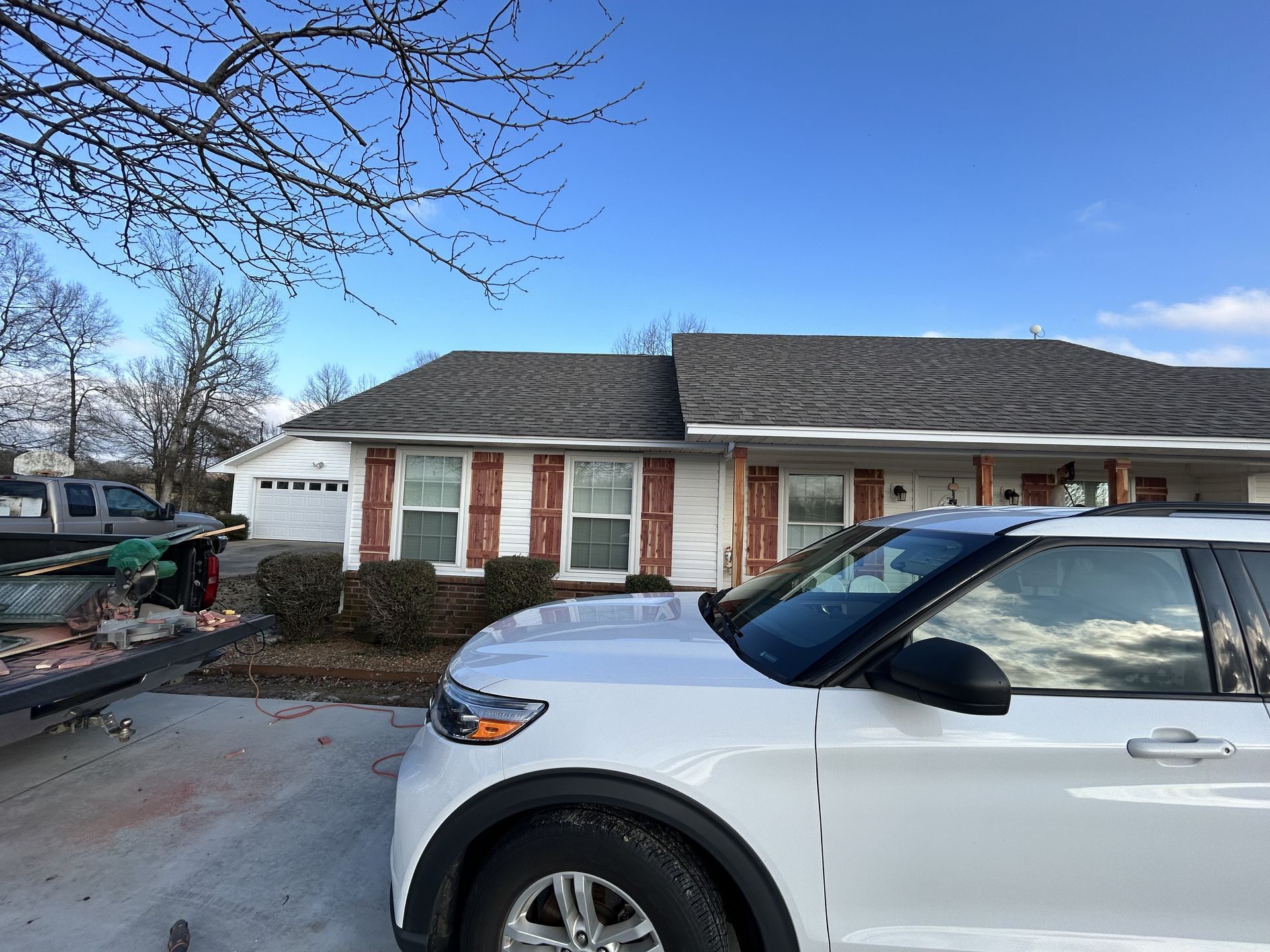 A white suv is parked in front of a house.