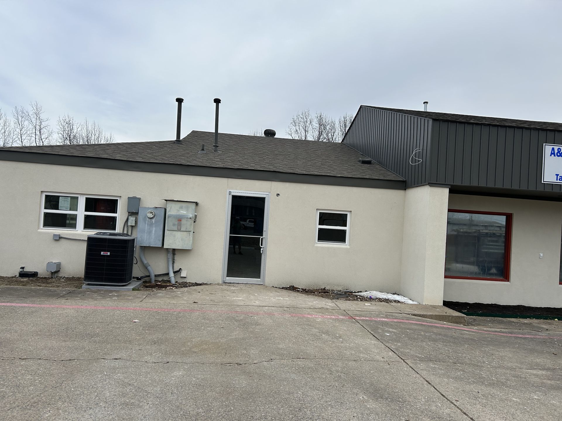 A white building with a gray roof and a sign on the side of it.
