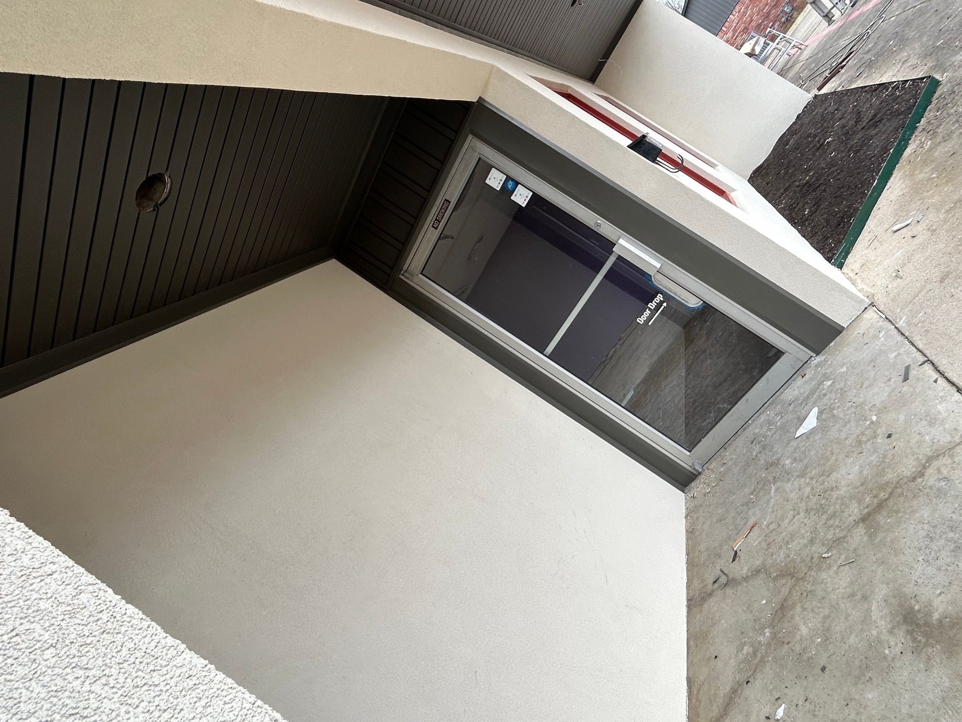 A white building with a sliding glass door and a sign that says ' elevator ' on it