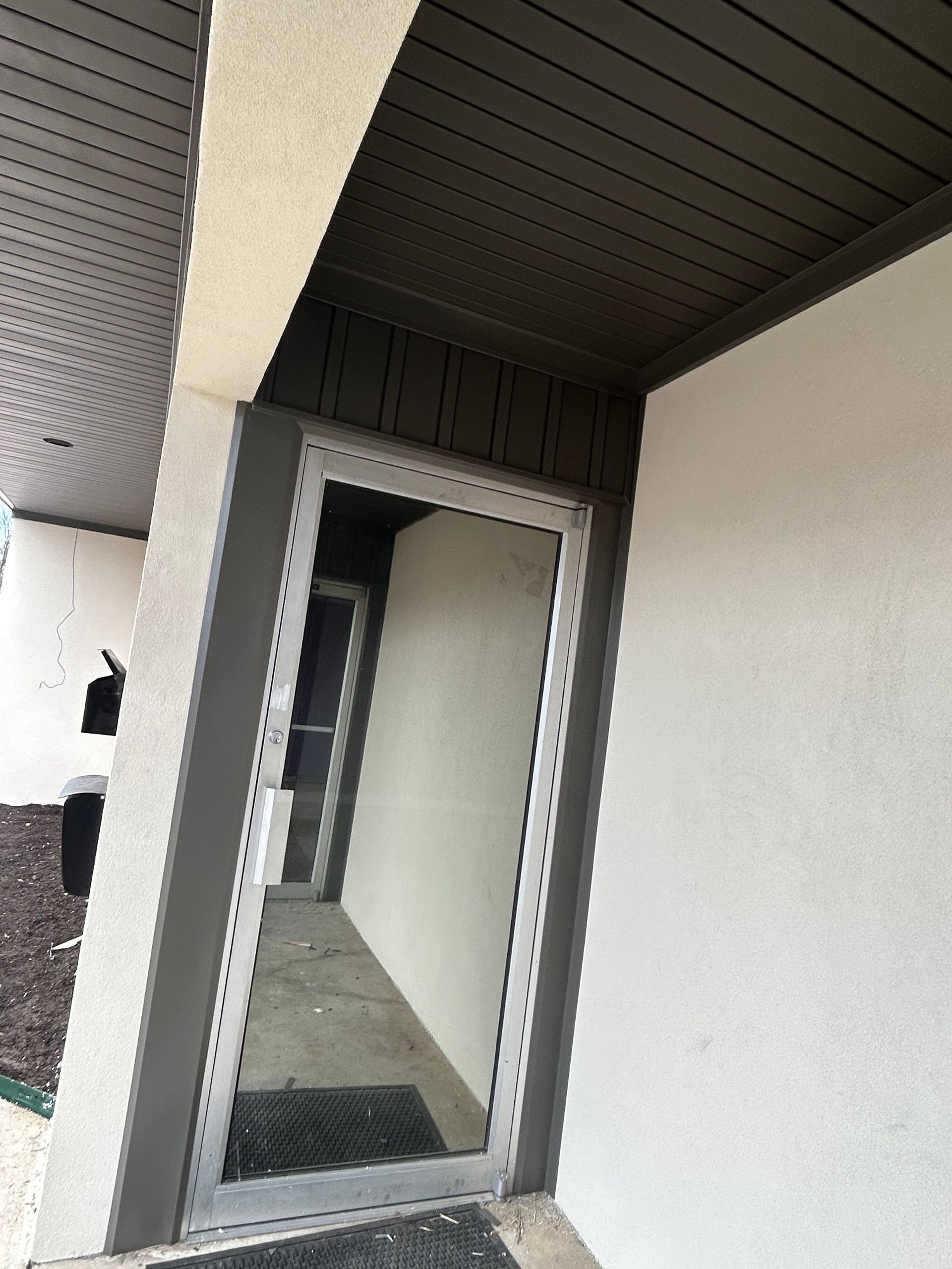 A door with a mirror on it is on the side of a building.