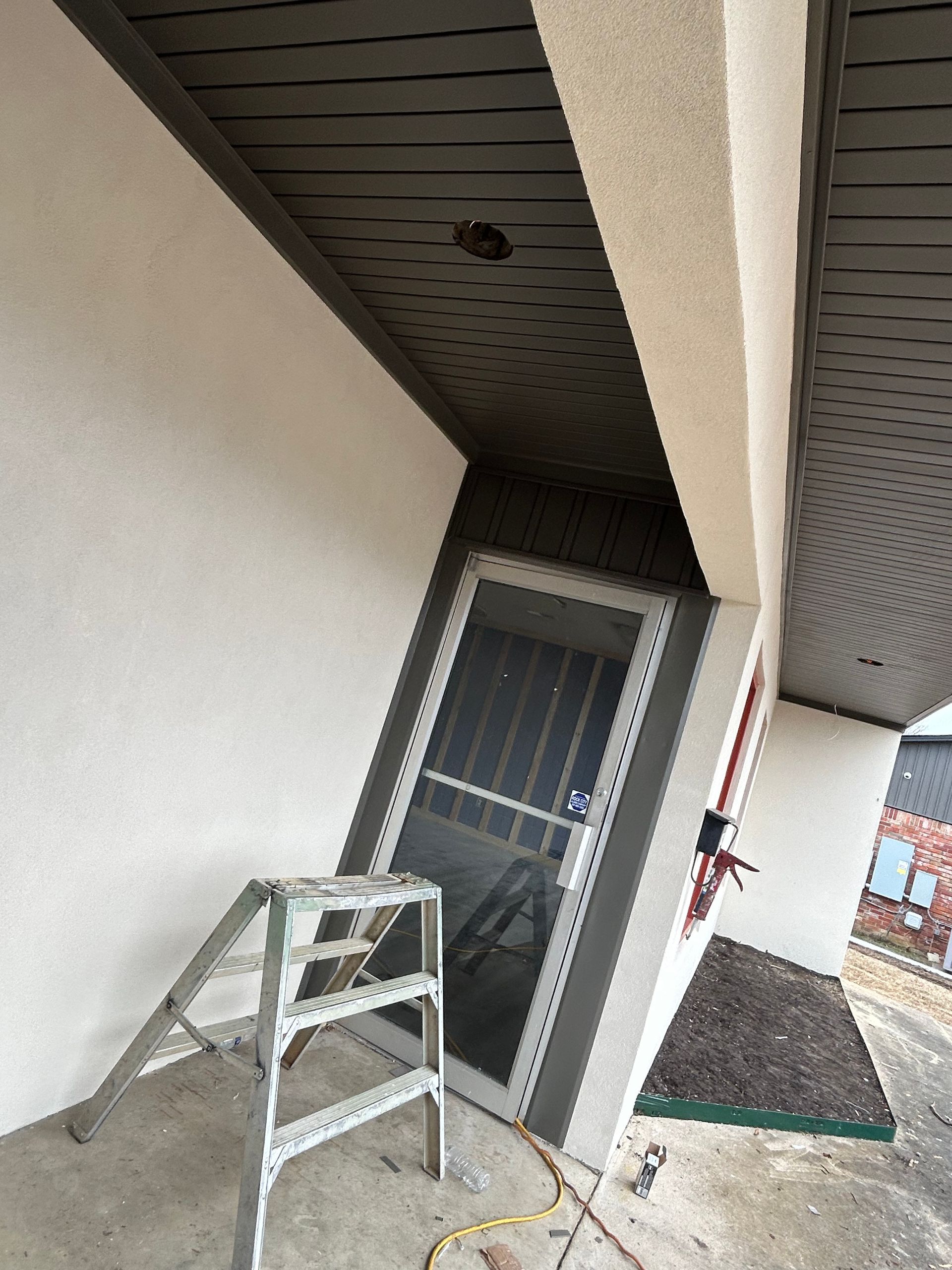 A ladder is sitting on a porch next to a screen door.