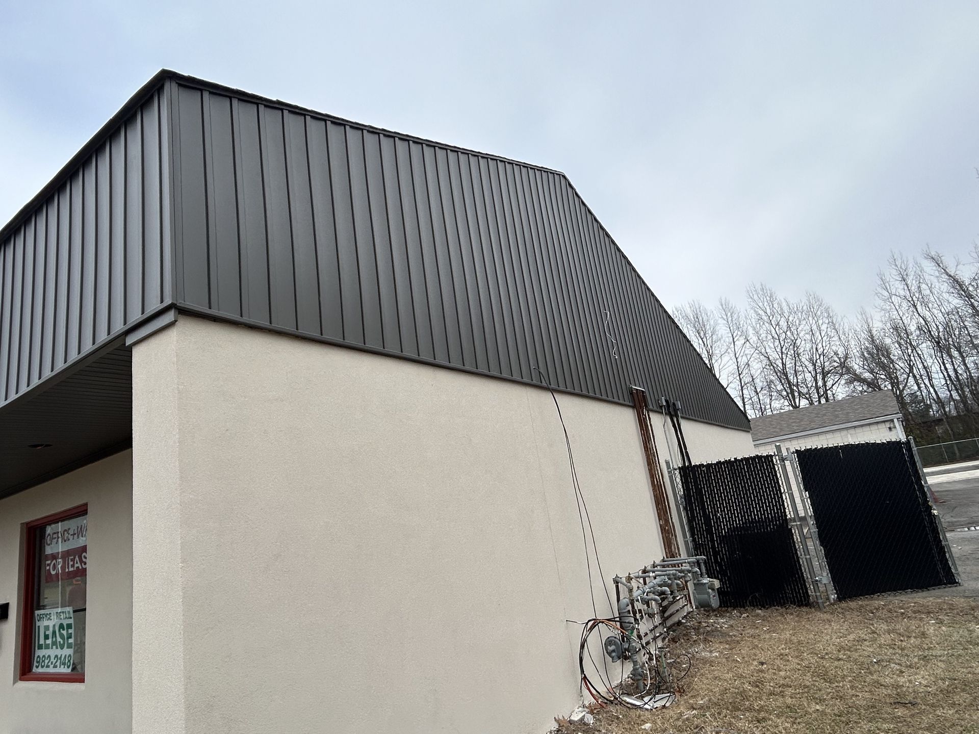 A white building with a black roof and a window