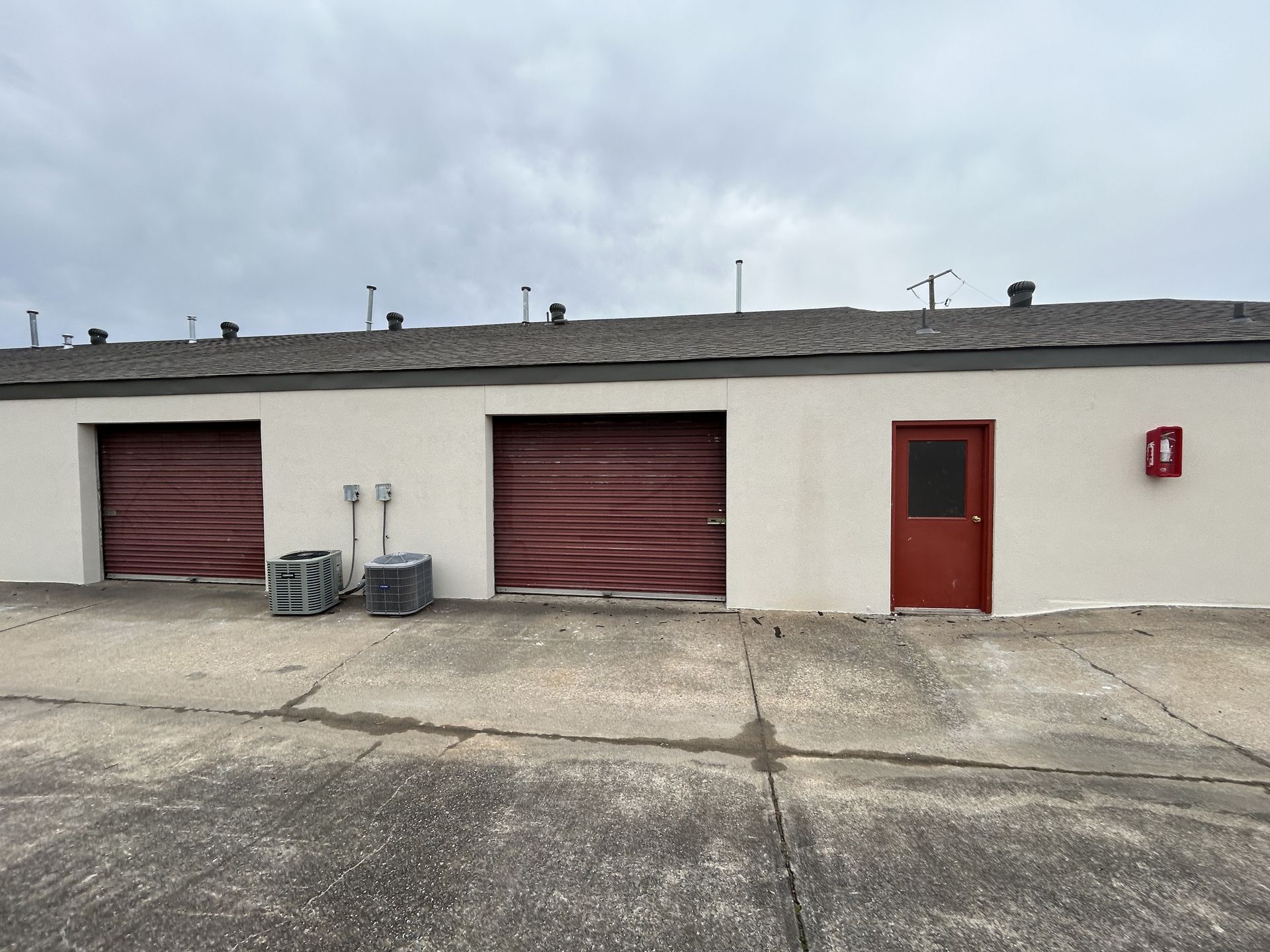 A white building with red garage doors and a red door.