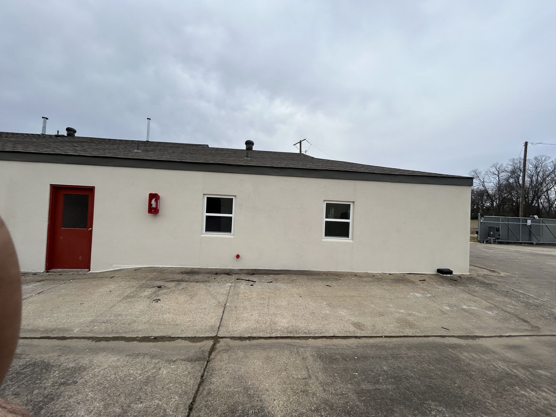 A white building with a red door and two windows
