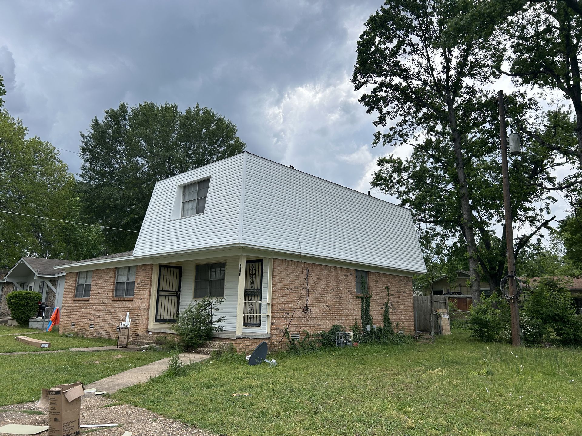 A brick house with a white roof and trees in front of it.