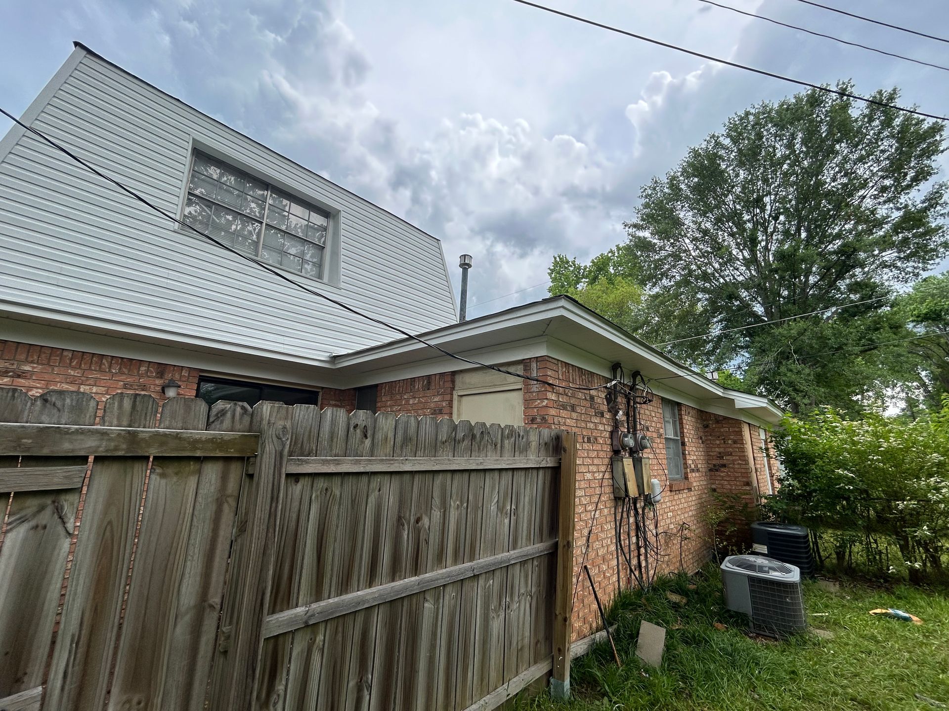 A brick house with a wooden fence in front of it.