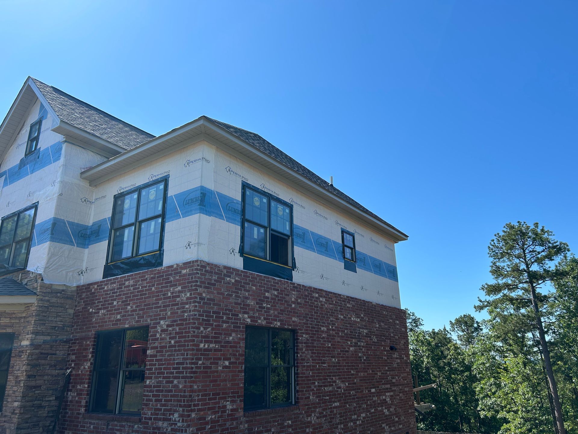 A brick house is being built with a blue and white stripe on the side.