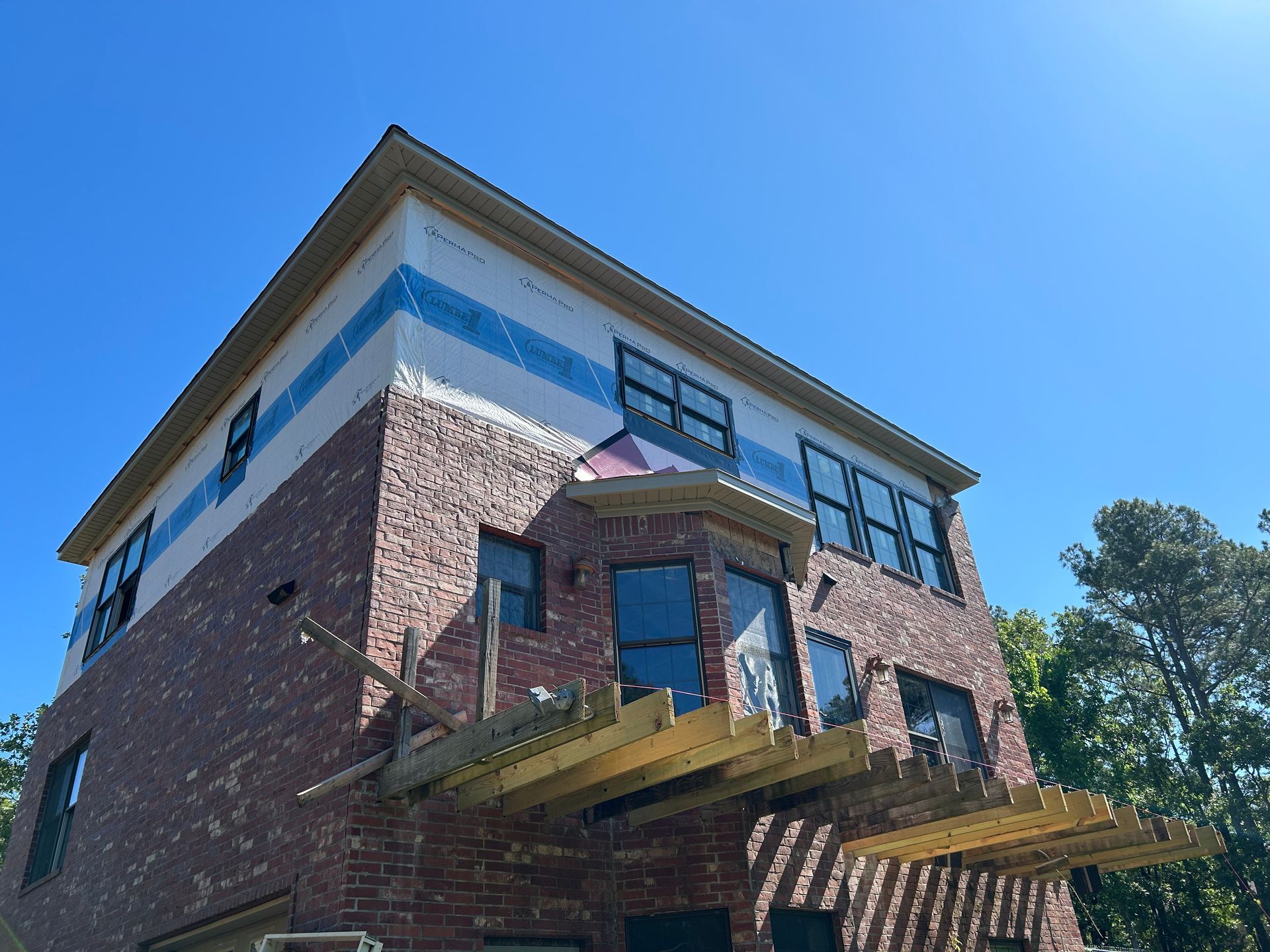 A large brick building under construction with a blue sky in the background.