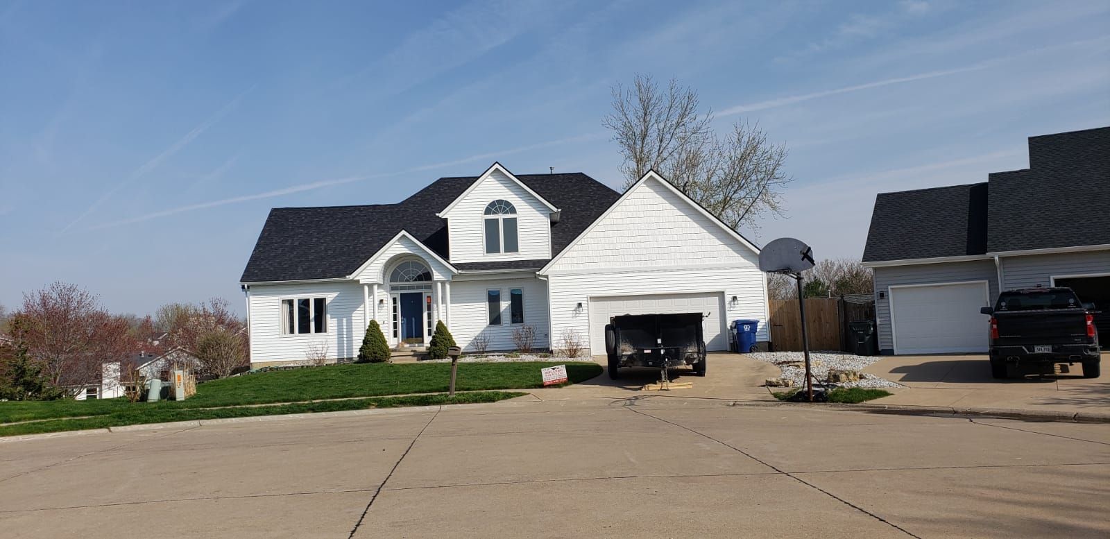 A white house with a black roof and a black truck parked in front of it.
