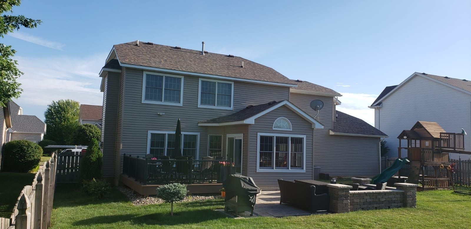 A large house with a lot of windows is sitting on top of a lush green lawn.