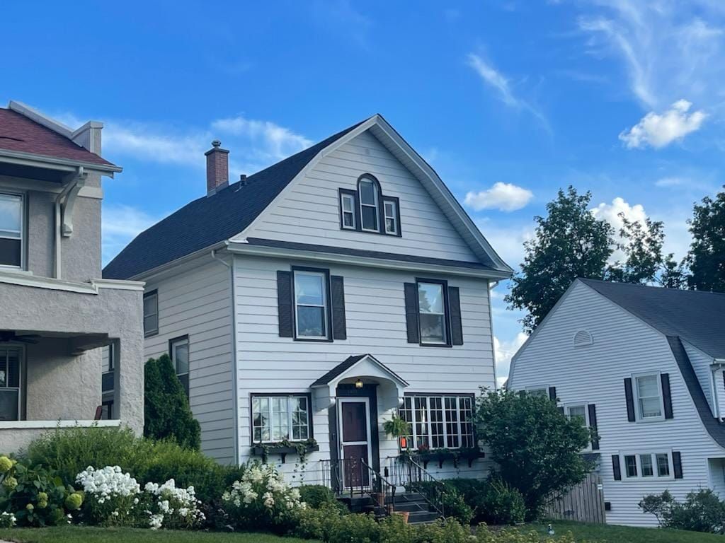 A white house with black shutters and a blue sky in the background