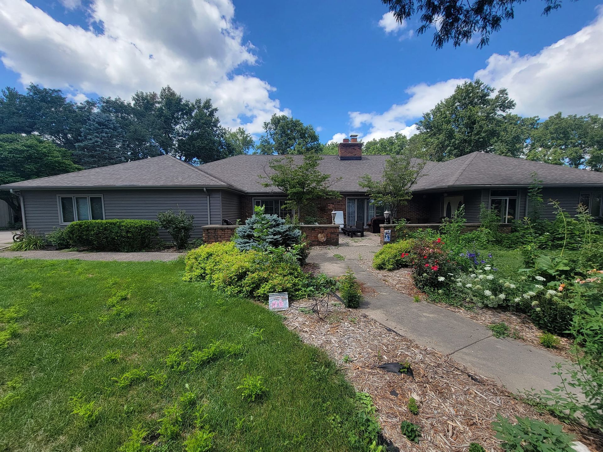 A large house with a gray roof and a walkway leading to it.