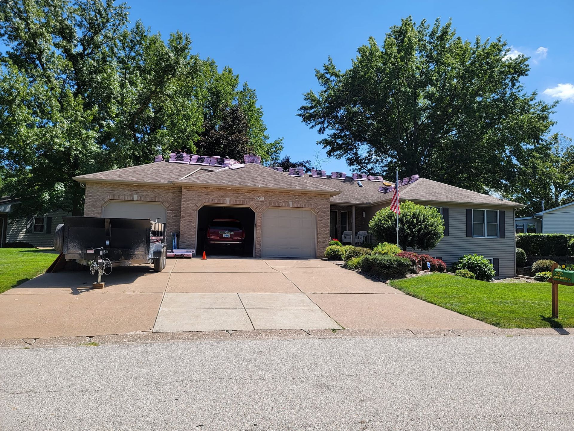A house with a car in the garage and a trailer parked in front of it.