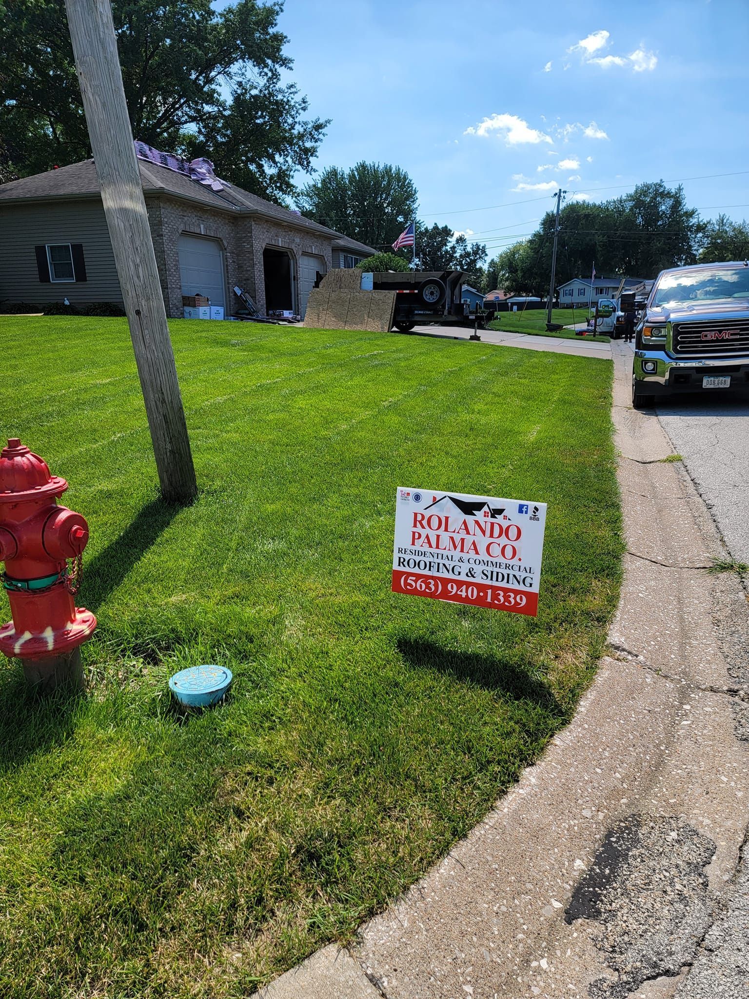A fire hydrant in the grass next to a house with a sign on it.