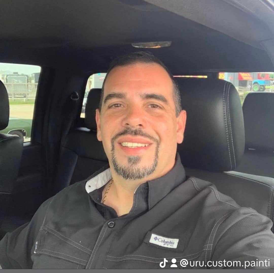 Two-story blue beach house with white trim, elevated on stilts. It has balconies, a white roof, and is set on a grassy lot.