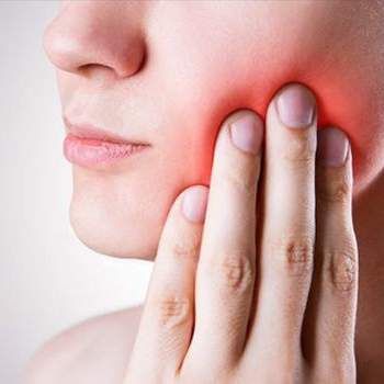 Person with hand on cheek, red area indicating pain; possible toothache.