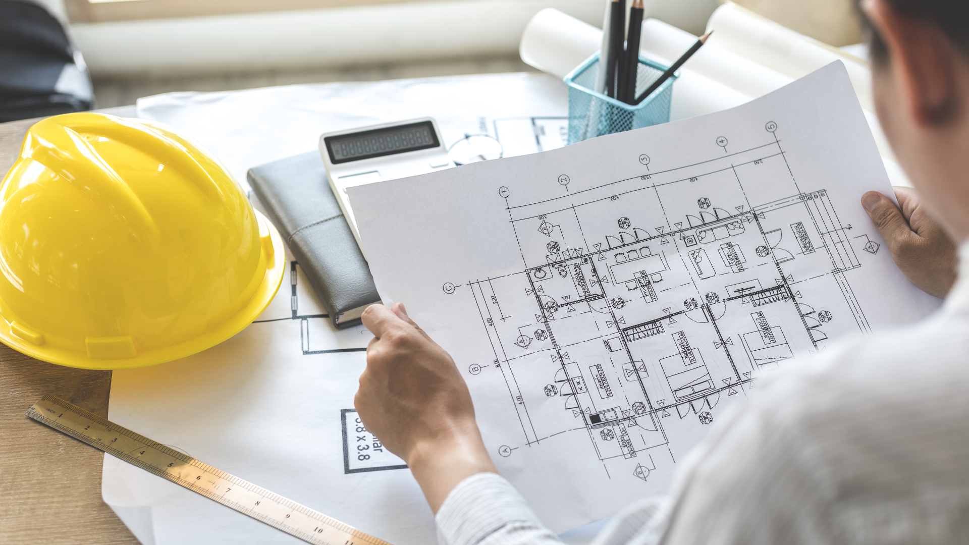 A man is sitting at a table looking at a blueprint.