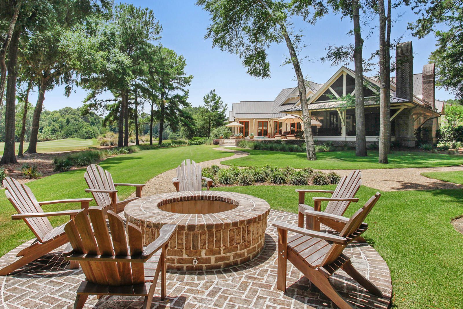 A fire pit with chairs around it in front of a house.