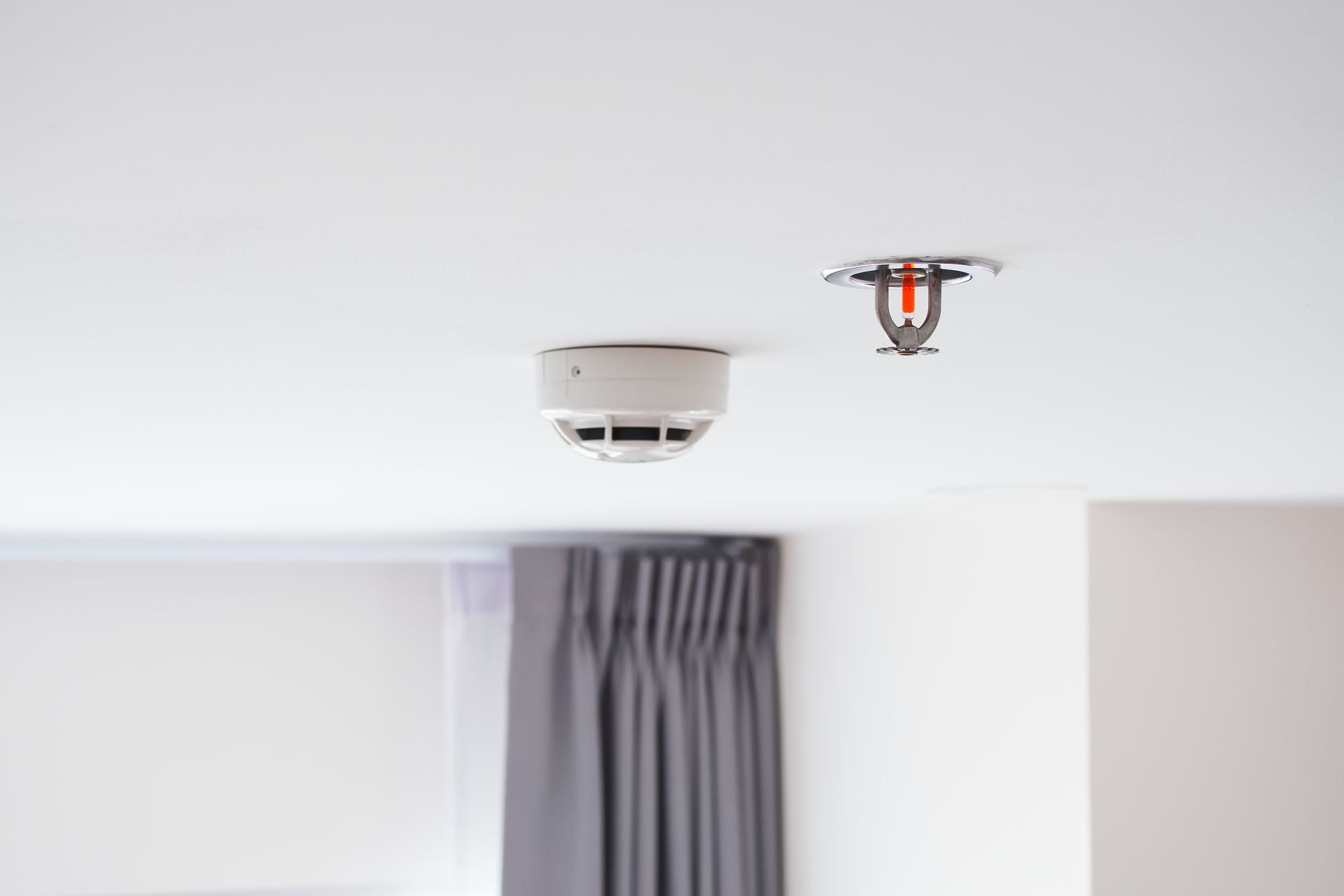 A smoke detector is hanging from the ceiling of a room.