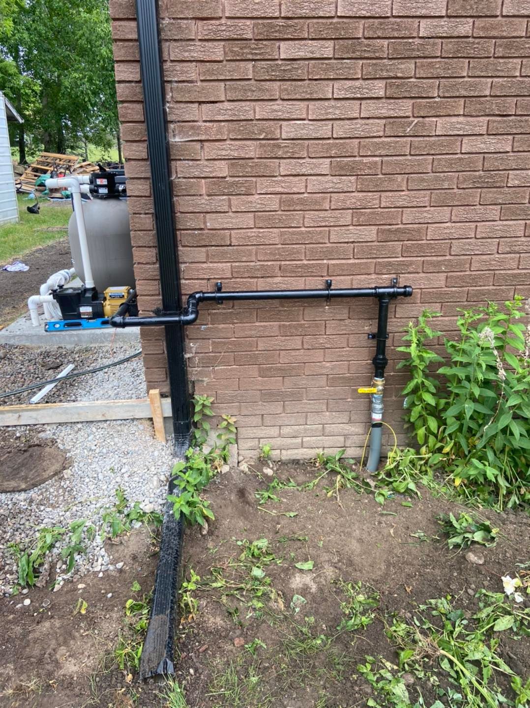 A brick wall with a black pipe attached to it.