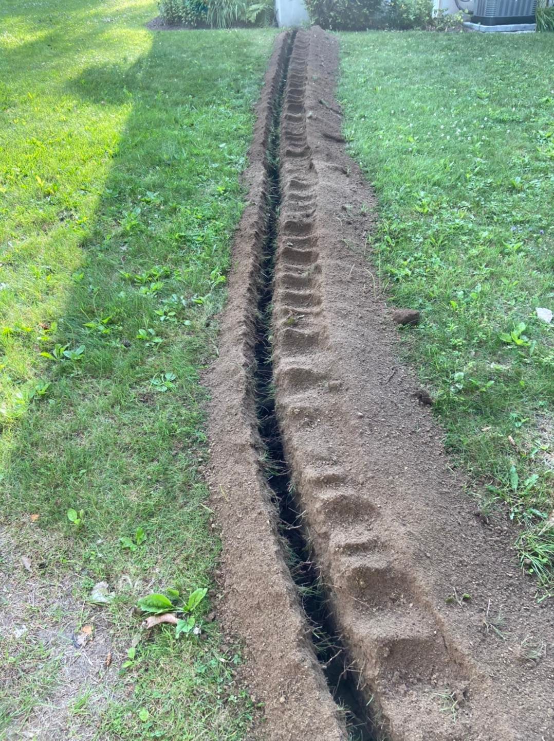 A drainage pipe is being installed in a yard.