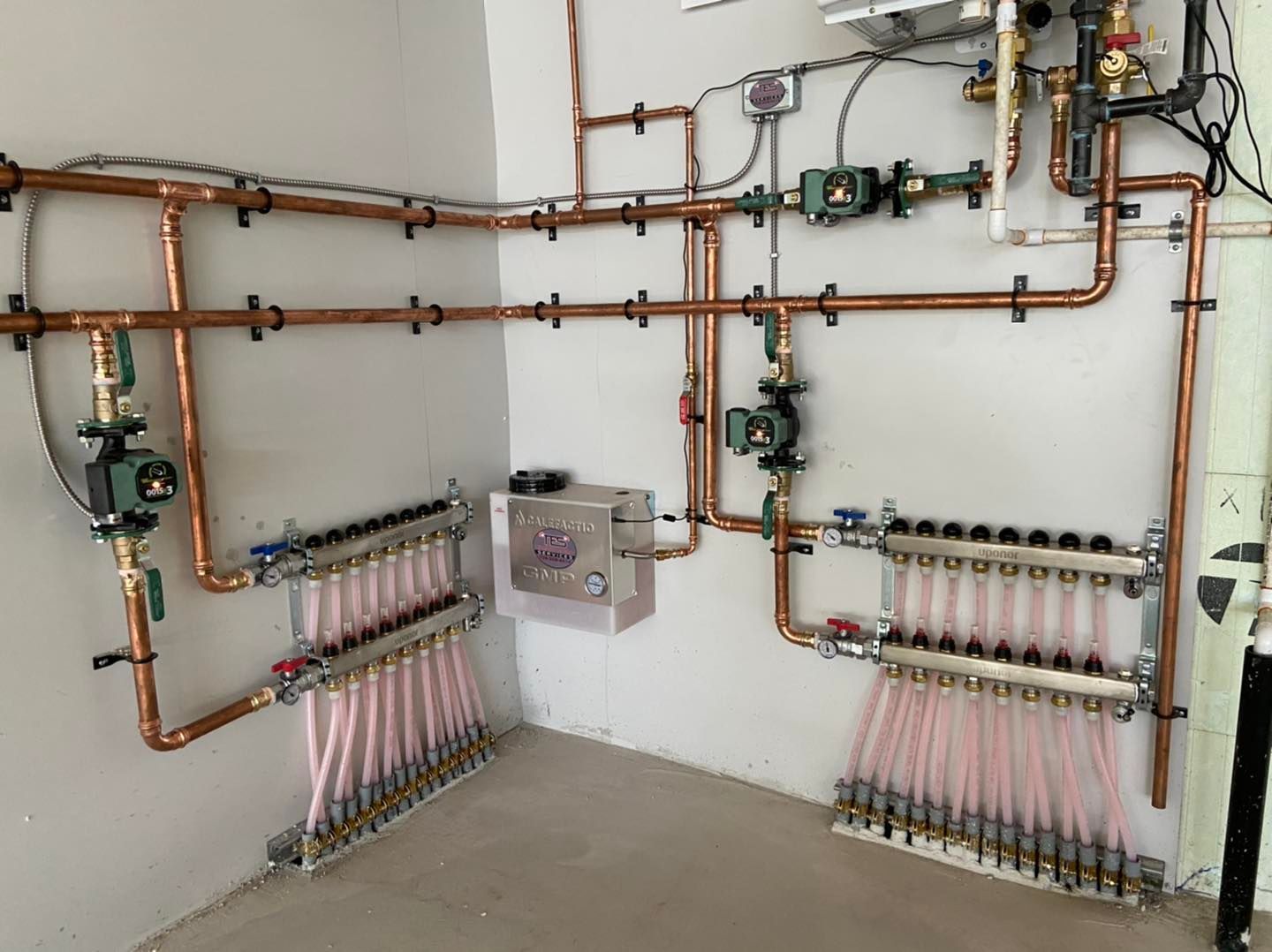 A room with a lot of copper pipes on the wall.