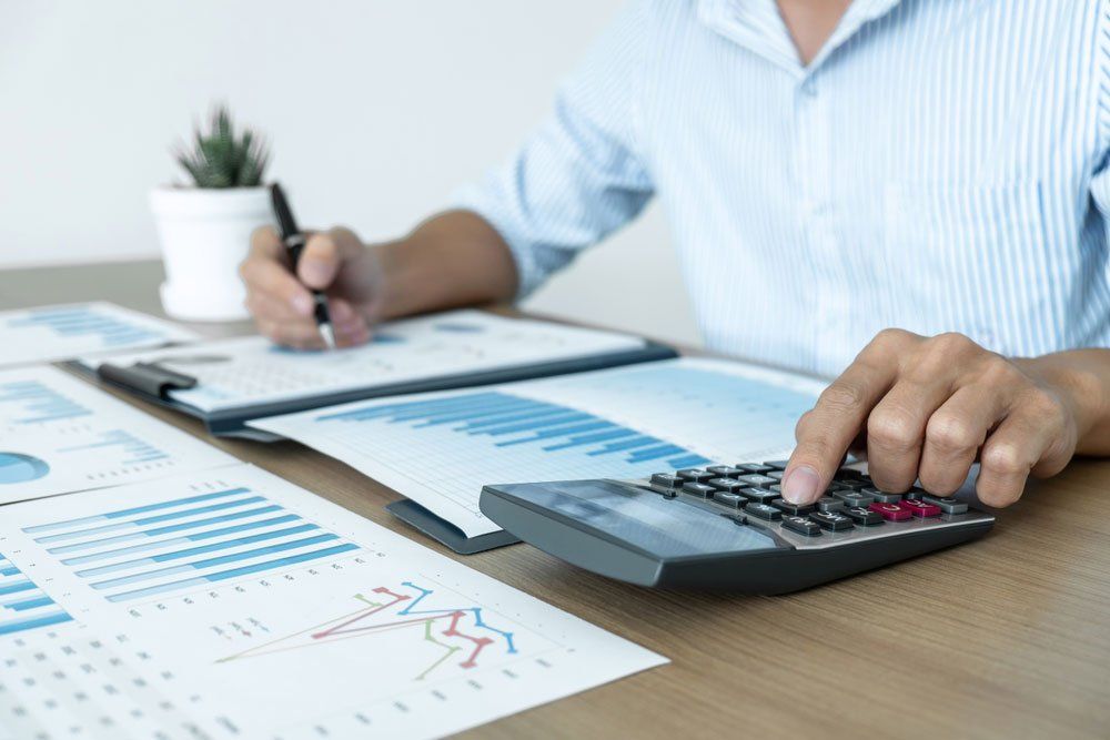 A Man Is Using a Calculator While Writing on A Clipboard — Cape York Accounting Smithfield in Smithfield, QLD