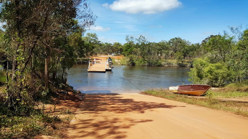 A Dirt Road Leading to A Lake with A Boat in The Water — Cape York Accounting Smithfield in Bamaga, QLD