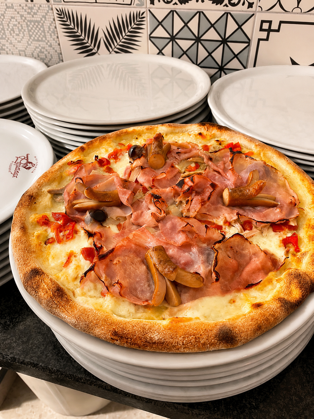 Una pila di ciotole sormontate da una piccola teglia al forno con prosciutto e formaggio fuso, appoggiata su un bancone della cucina.