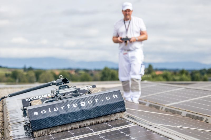 Ein Roboter reinigt Solarmodule auf dem Dach eines Gebäudes.