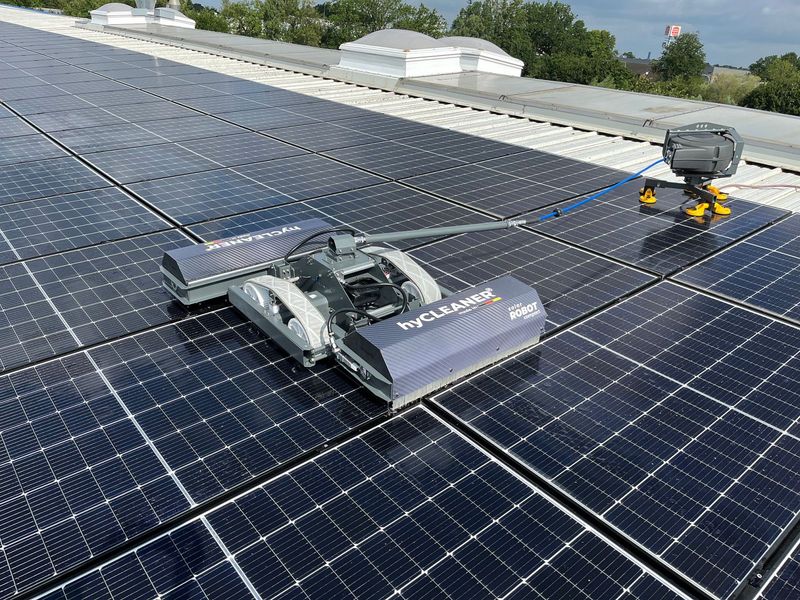 Ein Roboter reinigt Solarmodule auf dem Dach eines Gebäudes.