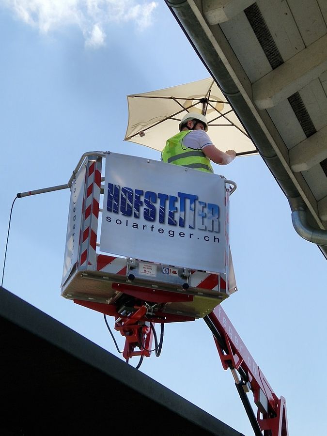 Ein Mann in einer Hebebühne  auf dem das Wort Hofsteiner abgebildet ist