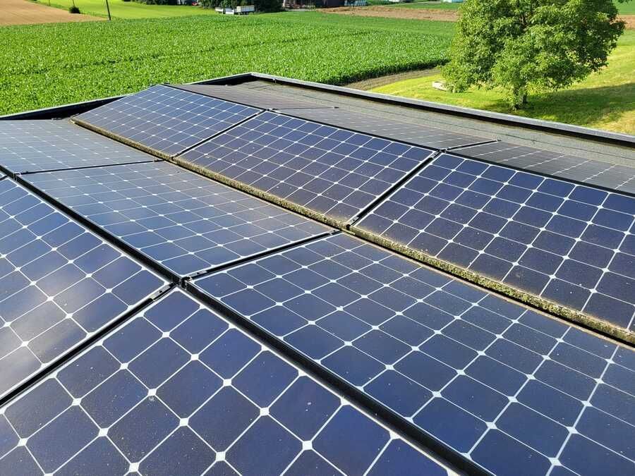 Eine Reihe von Solarmodulen auf einem Dach mit einem Feld im Hintergrund